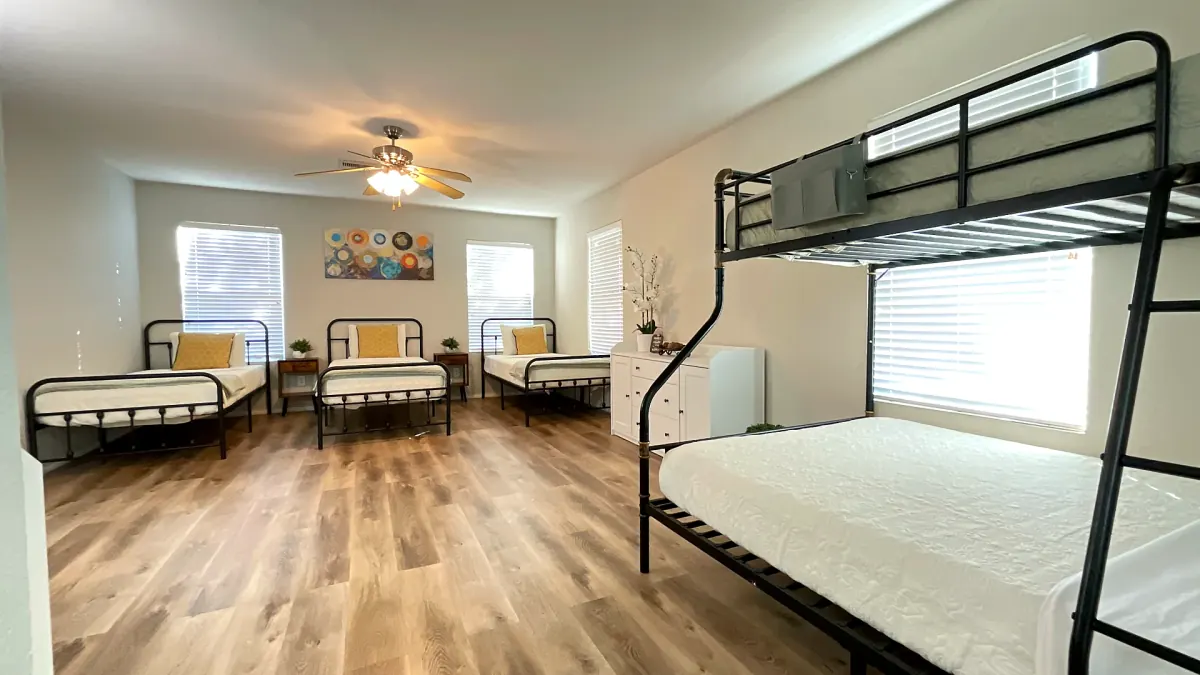 Bedroom with multiple real beds at Glampstead Retreat large group vacation rental in San Antonio